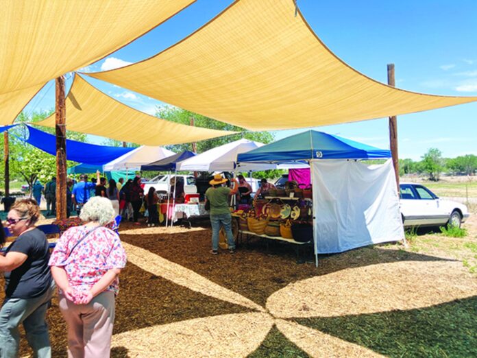 Customers visit the booths at the Española Farmers Market Monday.
