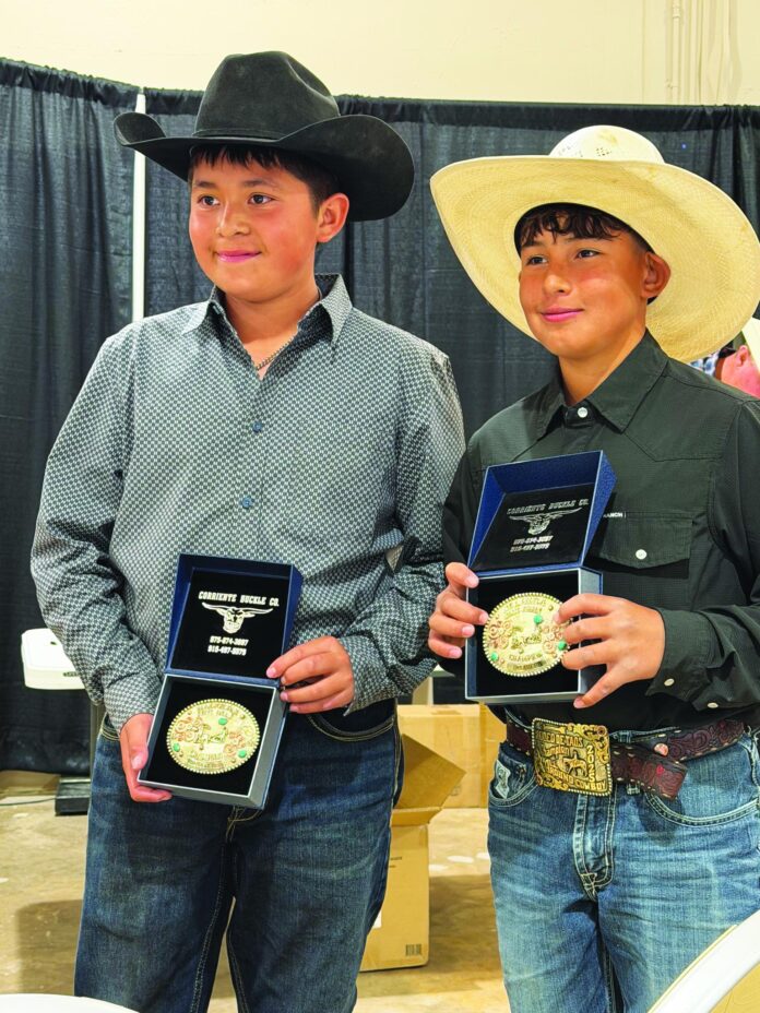 Nataani Garduño (left) and Antonio Montoya show off their team roping buckles.