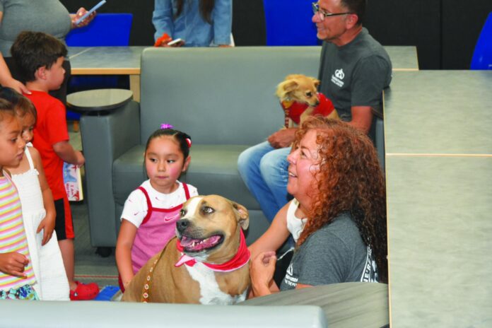 Española Humane’s Mattie Allen (right) and her pitbull-mix Jellybean at the Española public library.