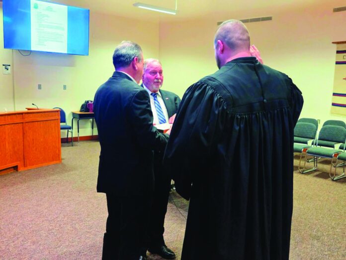 Española Police Chief Jack Jones (center) gets sworn into office on May 26 by Española Magistrate Judge Joseph W. Madrid, while Española City Councilor Stephen Salazar (left) holds the Bible. Jones is restructuring the department to raise the pay for two lieutenants and establish a captain position.