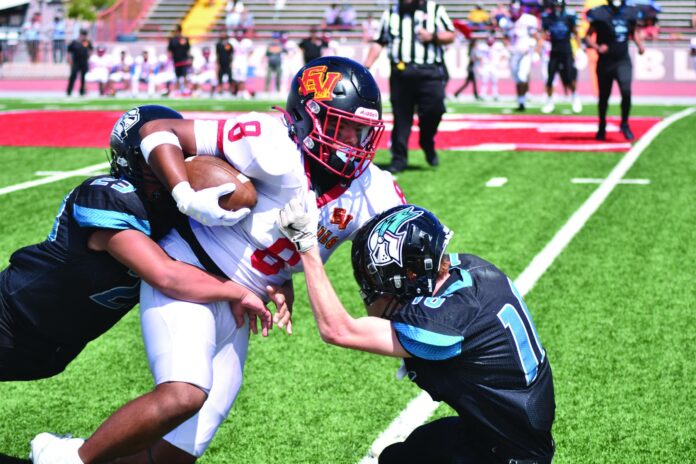 Española Valley junior Ariel Quintana tries to break through the hold of a couple of Del Norte defensive backs Saturday as the Sundevils won 64-14.